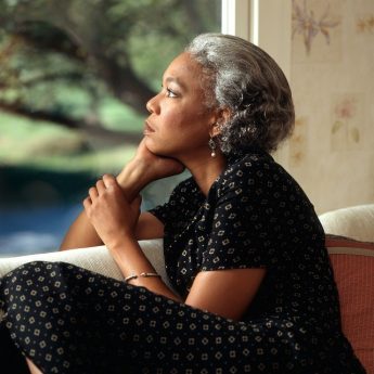mulher olha pela janela pensando em meditação e autocompaixão