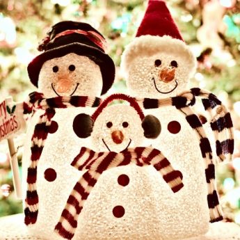 Três bonecos de neve com cachecol colorido