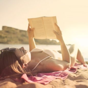 Mulher lendo um livro na praia ao sol
